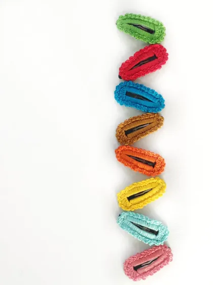 A simple, clean shot of our crochet barrettes lined up in a rainbow. This shows the variety of solid colors we offer.