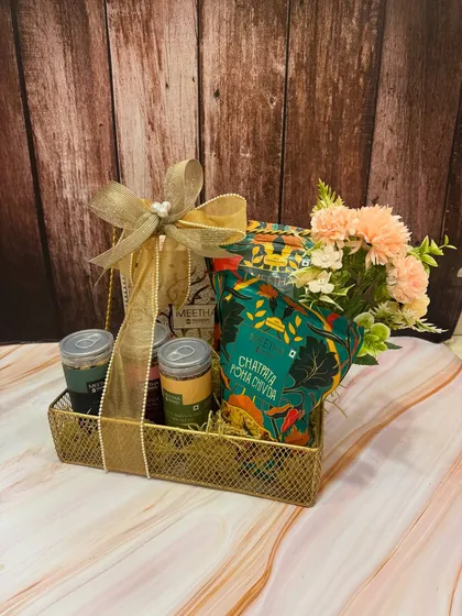 Have a 'Chatpati & Meethi' Rakhi with our desi snack hampers. This one features a variety of traditional Indian snacks with a modern twist, arranged in a golden mesh basket.