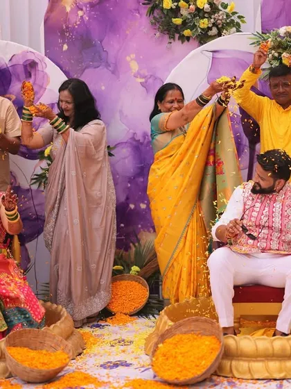 The Haldi rituals with the family. The couple sits in traditional brass 'urlis' as their parents apply haldi and shower them with marigold petals.