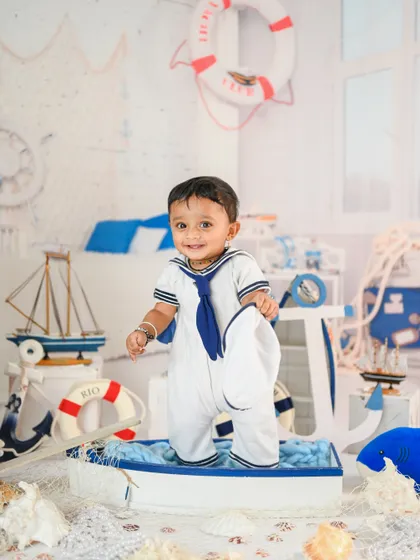 Ahoy, little sailor! This nautical-themed setup with a boat, lifebuoy, and sailor outfit is perfect for an adventurous little one.
