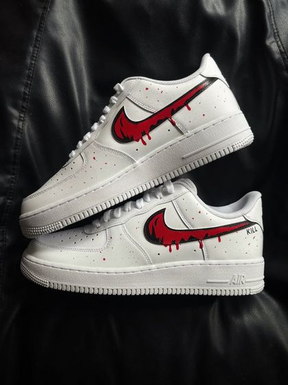 A clean white Nike Air Force 1 with a blood-red dripping swoosh and subtle red splatter.