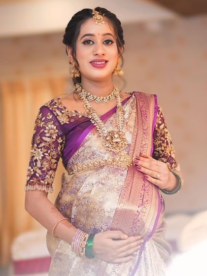 This purple net blouse was a joy to create for my dear client Sowmya's baby shower. The sheer sleeves are adorned with delicate, hand-embroidered floral vines in gold threadwork, creating a look of ethereal elegance for her special day.