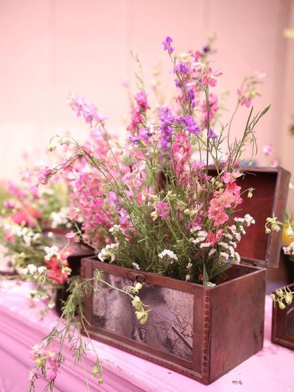 A charming and rustic floral arrangement. Wildflowers in shades of pink and purple are placed in a vintage wooden box, adding a personal and nostalgic touch to the decor.