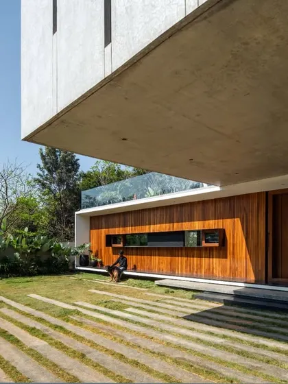 A low-angle view emphasizing the powerful form of the cantilevered concrete slab. This structural element provides a sheltered outdoor space, seamlessly connecting the home's interior with the garden and lawn.