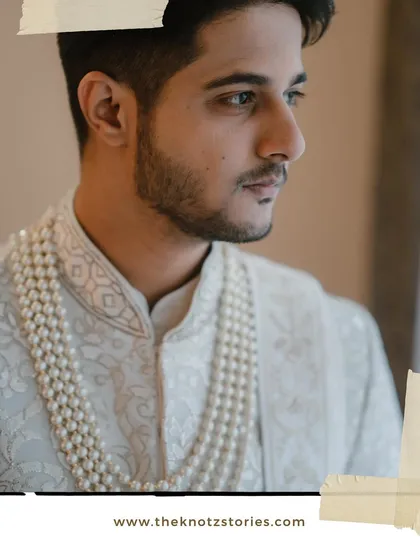 A handsome side-profile portrait of the groom, highlighting his sharp features and elegant pearl necklace.