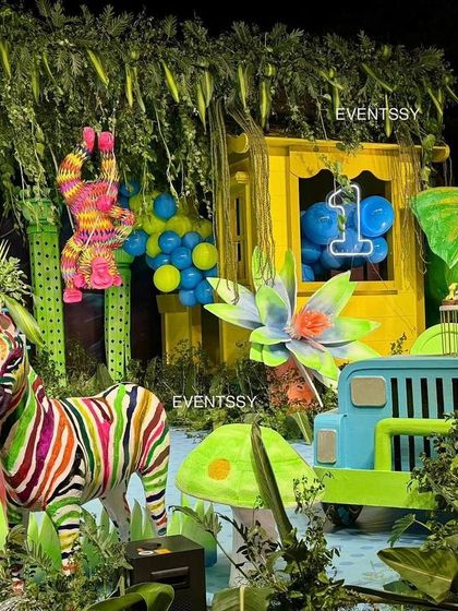 A closer look at the neon jungle, featuring colorful zebras, an elephant, and a jeep prop. The use of bright, contrasting colors against the dark background makes the whole scene pop.