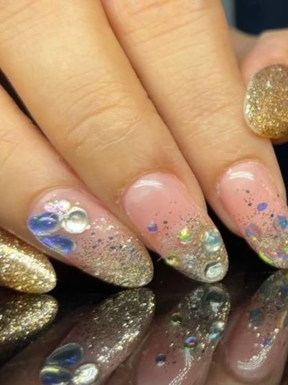 A luxurious manicure combining full-coverage gold glitter nails with sparkling glitter and rhinestone accents on a sheer base.