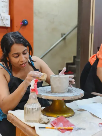 A student in our sgraffito workshop carefully refines the surface of her pot. This process involves smoothing the clay with a sponge to prepare it for carving, ensuring a clean and beautiful final piece.
