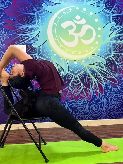 This advanced backbend, performed while seated on a chair, highlights extreme spinal flexibility and control.