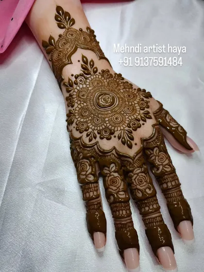 The mandala is a centerpiece of many henna designs. Here, a detailed central mandala is framed by an elegant wrist cuff and delicate rose patterns on the fingers, showing how to combine major elements for a cohesive look.