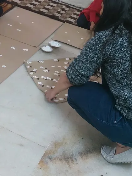 A participant is fully engaged in creating her snowman-patterned wrapping paper. These hands-on activities are designed to be both fun and skill-building, even for adults.