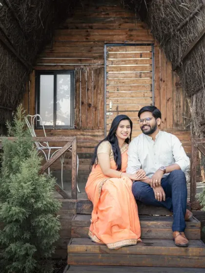 A lovely portrait of a couple sitting on the steps of a charming A-frame cabin. This setting in the woods provides a cozy and intimate backdrop for a pre-wedding photoshoot.