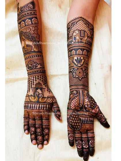 This design tells a story with a bride holding a diya (lamp) on one arm and an elephant in a royal procession on the other. The hands feature swans and peacocks.