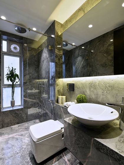 This bathroom is clad in dark, dramatic marble for a luxurious and moody feel. The backlit mirror and vessel sink add a modern touch, creating a perfect balance of classic and contemporary.