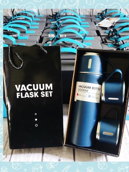 A view of the blue vacuum flask set next to its gift box and bag, showing the complete, premium presentation.