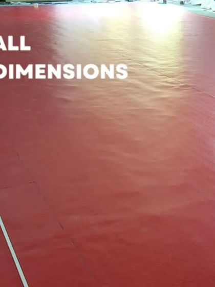 Laying down the red sports flooring mat during installation. The material comes in large rolls for a seamless, professional court finish.