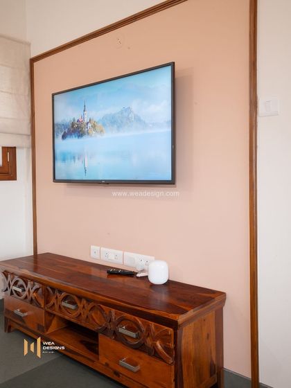 A simple TV unit made of solid Sheesham wood with carved details, adding a touch of traditional craft to a modern setting.