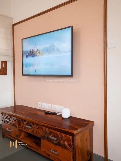 A simple TV unit made of solid Sheesham wood with carved details, adding a touch of traditional craft to a modern setting.