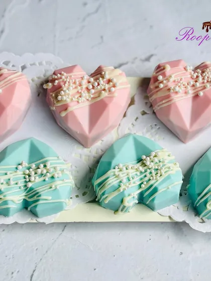 These geometric heart treats are a unique addition to a gender reveal party. Coated in pink and blue chocolate with a white chocolate drizzle, they can be filled with a surprise color inside.
