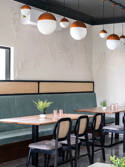 Every restaurant needs versatile spaces. I created this private dining niche for larger groups, using CNC-cut wood leaves on the wall to add a subtle, whimsical texture. The bleached wood tables and frosted glass pendants create a calm, complementary atmosphere.
