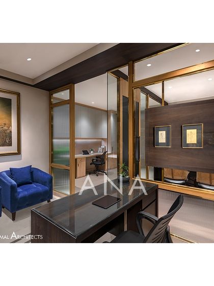 The reception desk at Jain Cosphere Office, clad in dark and light veneers. The desk is positioned to provide a clear view of the MD cabin and conference room entrances.