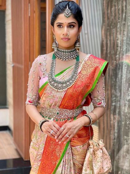 The full look is a beautiful blend of contemporary and classic styles. The makeup ties together the soft pink blouse and the unique jewelry.