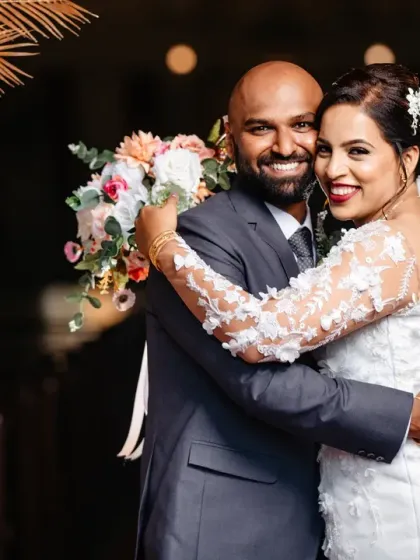 A happy, relaxed portrait of the bride and groom. Their comfortable embrace and genuine smiles show the easy joy of being newly married.