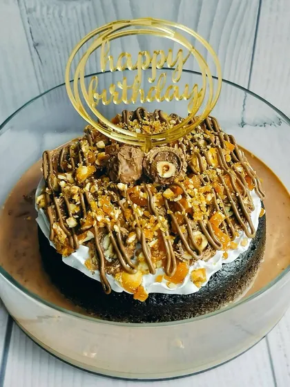 My Choco Rocher Tres Leches cake is pure indulgence. It's a moist chocolate sponge topped with hazelnut praline, drizzled with chocolate, and finished with Ferrero Rocher chocolates.