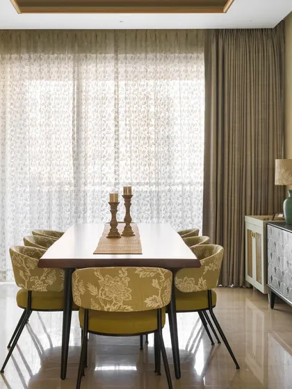 A closer look at the dining area in the Ivy Nest, with chartreuse floral chairs and a simple, elegant table setting. The sheer curtains diffuse the natural light beautifully.