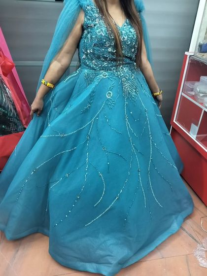 A beautiful turquoise blue gown with silver embroidery, perfect for a pre-wedding shoot or a reception party. The cape sleeves add a modern, stylish touch.