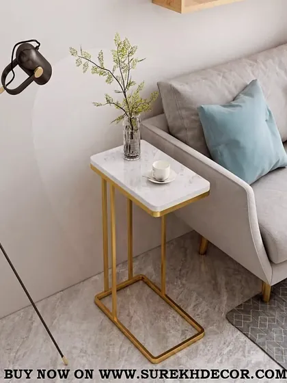 This stylish side table features a rectangular white marble top on a shiny golden C-shaped base. The clever design allows it to slide easily under a sofa, making it a perfect spot for a cup of coffee or a laptop.