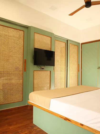 The sliding cane wardrobe incorporates a central panel for mounting a TV, a clever solution for saving space in a bedroom.