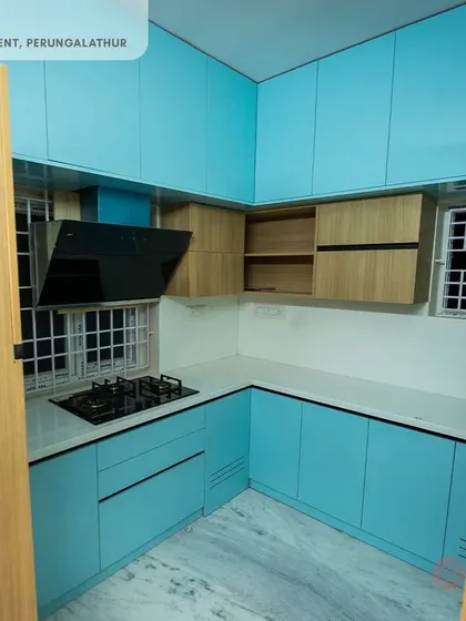 We love playing with color to bring personality into your home. This L-shaped modular kitchen features a refreshing dual-tone combination of vibrant blue and warm wood, finished with high-gloss laminates for a sleek, contemporary look.