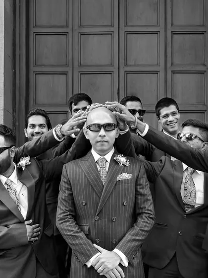 The groom and his groomsmen share a fun, playful moment. This black and white photo captures the camaraderie and joy of friendship on a wedding day.