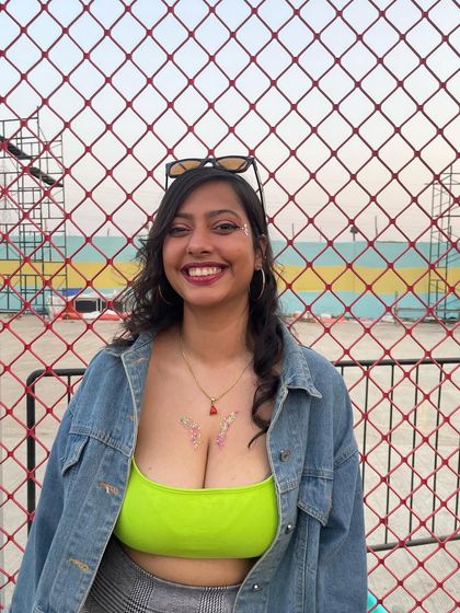 A client in a neon top with delicate floral glitter art on her chest. The subtle sparkle is a great contrast to her bright outfit.