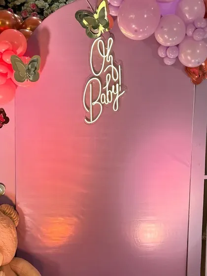 The 'Oh Baby' neon sign glows against the pastel backdrop, surrounded by fluttering butterflies.
