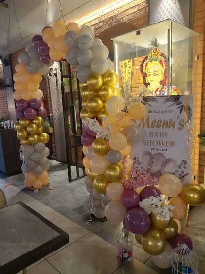 The entrance setup for 'Meena's Baby Shower', featuring a balloon arch and a personalized welcome sign.