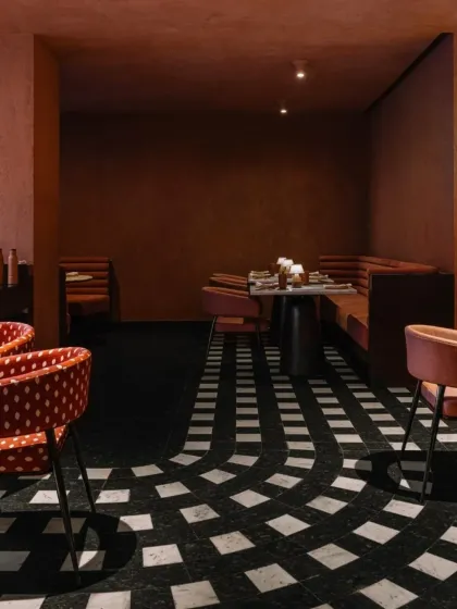 The flooring at Idylll features a dynamic pattern of black and white granite, creating a sense of movement that guides guests through the different zones of the restaurant.