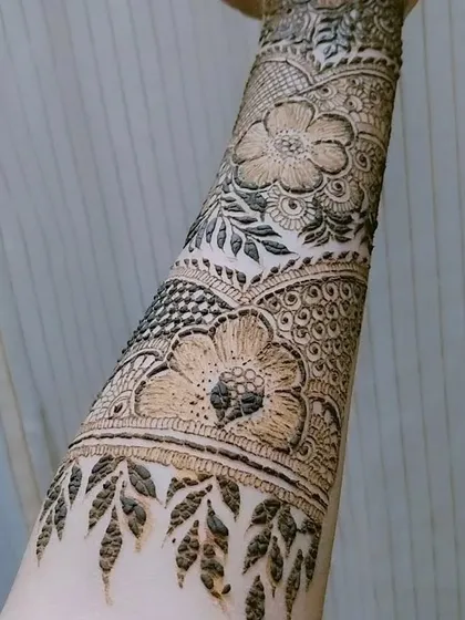 A close-up on the forearm portion of a bridal design, highlighting the beautiful floral bands and leafy vine patterns.