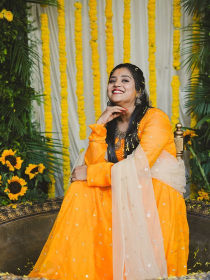 A portrait of the bride-to-be at her Haldi function. The decor features a mix of marigold strings and sunflowers, creating a bright and sunny theme for her special day.