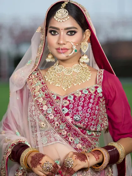 A beautiful outdoor shot of a bride. The natural light shows off the flawless HD makeup and the intricate details of her lehenga.
