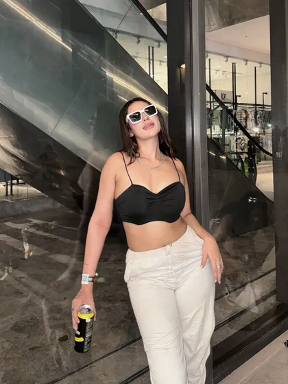 A casual party look with a black crop top, white trousers, and statement sunglasses.