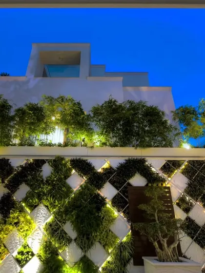 This design combines a geometric vertical garden with modern architectural elements on a multi-level building. The integrated lighting highlights the pattern at night, turning the building's facade into a dynamic, living feature.