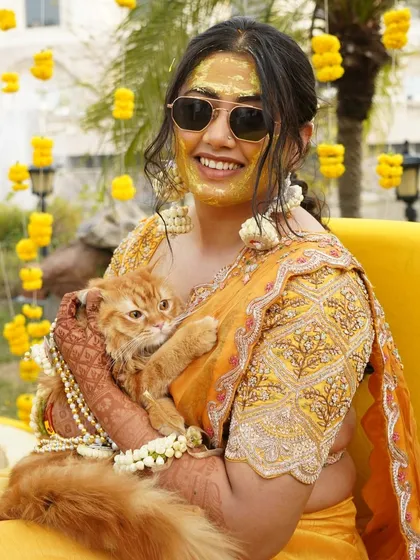 A fun and unique moment as the bride, with Haldi on her face, poses with her adorable cat.