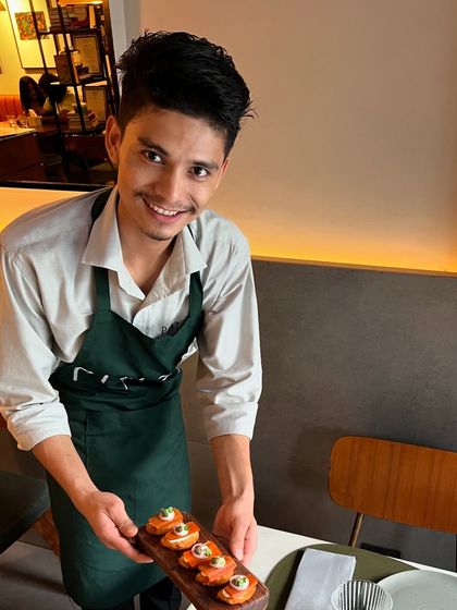 One of our smiling team members, ready to serve our prawn croquettes.