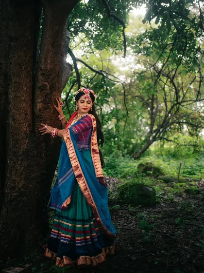 A full-length portrait capturing the grace of Radha amidst a verdant forest, her colorful attire standing out against the natural backdrop.