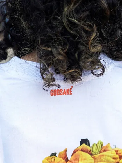 A detail shot of the Godsake logo placement on the back neckline of the white graphic tee.