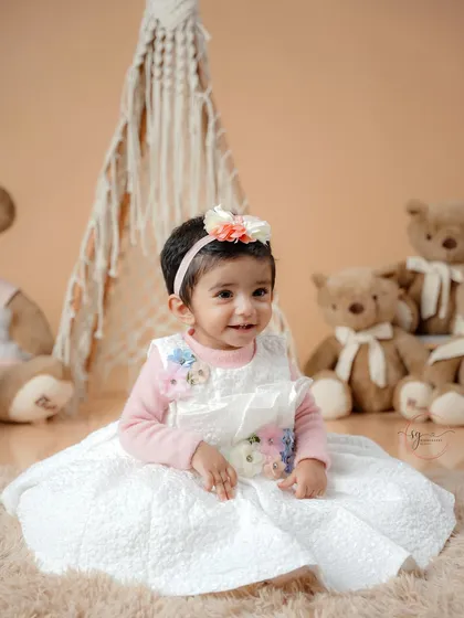 A close-up shot highlighting the beautiful details of the baby's dress and the soft, gentle expression of the birthday girl.