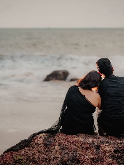 The couple sits on a rock, looking out at the ocean together. This peaceful, reflective moment captures the feeling of finding your person to share life's views with.