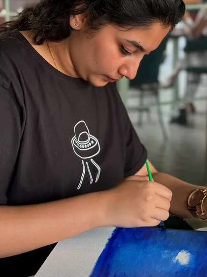A participant deeply focused on her painting of a night sky. The concentration in the room is always palpable.
